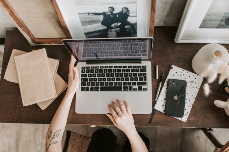 An aesthetic workspace featuring a laptop, smartphone, and stationery items from a top-down view.